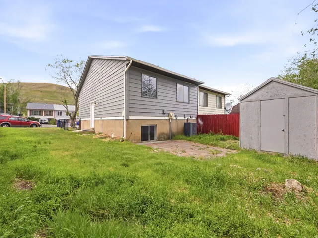 Expansive grassy yard with a gray siding structure and a separate storage shed