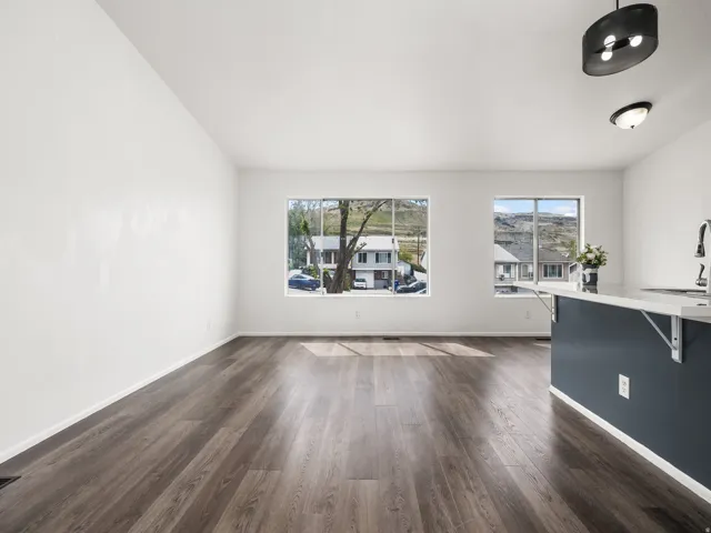 Open-concept living space featuring wood-finish flooring, white walls, and multiple windows