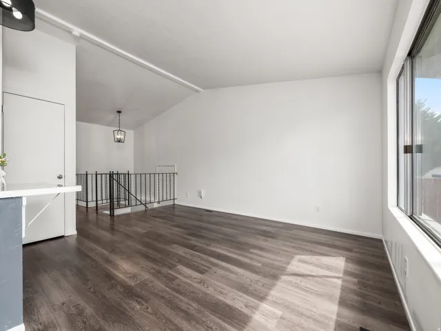 Spacious room featuring wood-finish flooring, white walls, and a large window