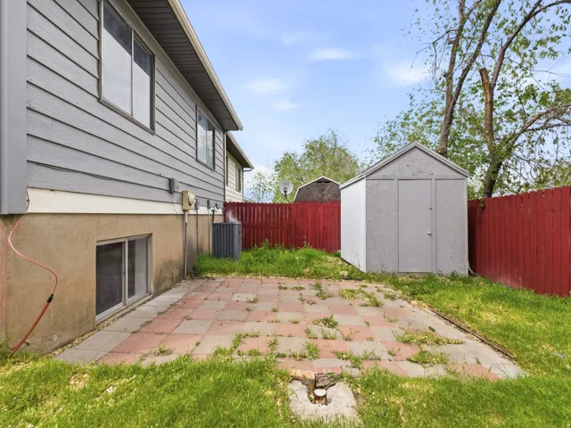 Exterior featuring gray siding, a red privacy fence, and a paver patio