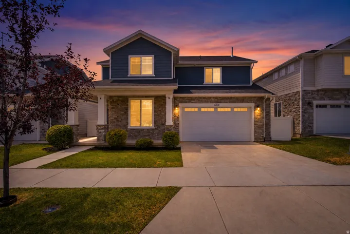 Two-story residence featuring a stone and siding exterior, an attached two-car garage, and a concrete driveway