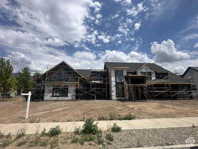 New construction residential structure featuring a dark shingle roof and a combination of wall sheathing and house wrap