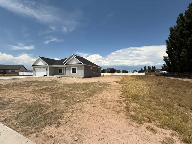 Contemporary ranch-style residence featuring a prominent two-car garage, dark shingle roofing, light gray vertical siding, and a contrasting white trim