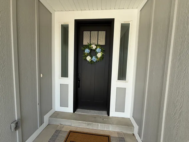 Black paneled entry door with clear glass inserts, framed by two sidelight windows