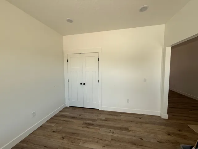 Room featuring wood-finish flooring, recessed lighting, and a white bi-fold door with black hardware