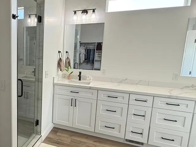 Contemporary bathroom featuring a dual vanity with white shaker-style cabinetry, quartz countertops, and matte black fixtures