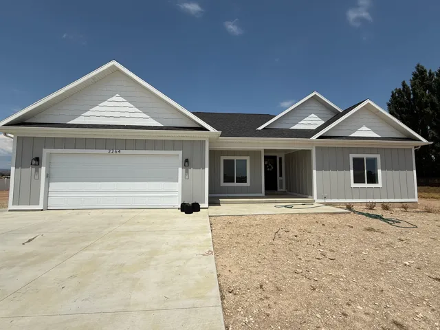 Contemporary single-story residence featuring light gray vertical siding and white trim