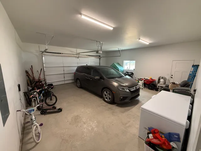 Spacious garage featuring a concrete floor, overhead fluorescent lighting, and a white paneled garage door