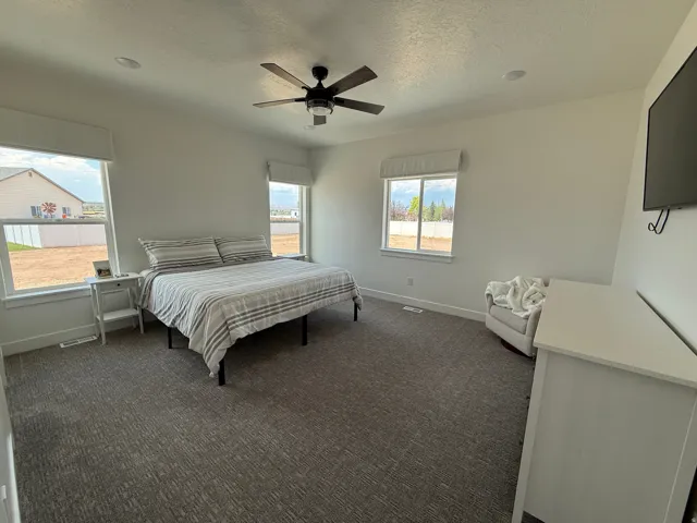 Spacious room featuring multiple windows, recessed lighting, a ceiling fan, and textured carpeting