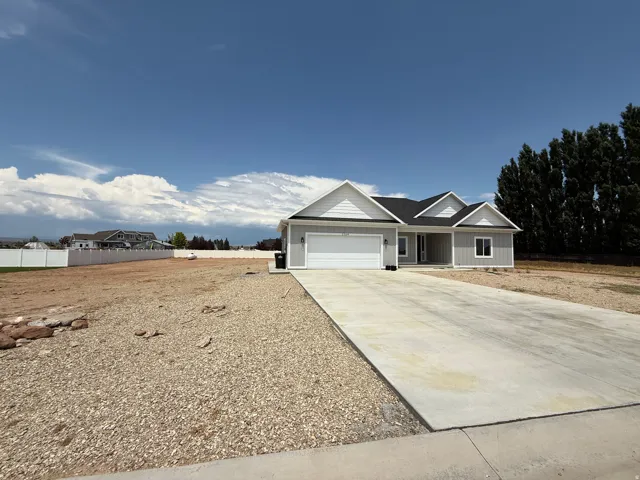 Contemporary ranch-style home featuring light gray siding, white trim, a dark shingle roof, and an attached two-car garage