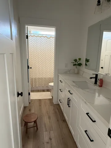 Bathroom featuring a double vanity with white cabinetry, integrated sinks, and light-colored countertops