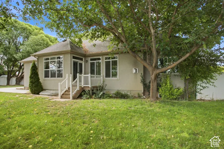 Rear exterior featuring multiple windows, a sunroom, and a wooden deck with white railings