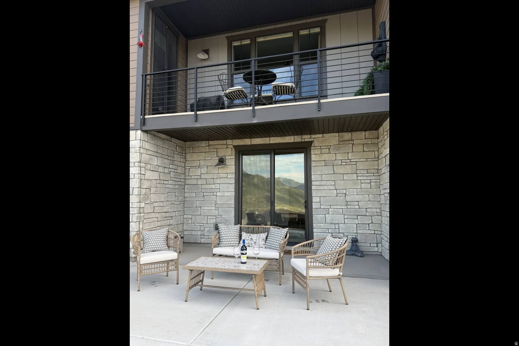 Stacked outdoor living spaces featuring a ground-level patio and an upper-level balcony, both with sliding glass door access