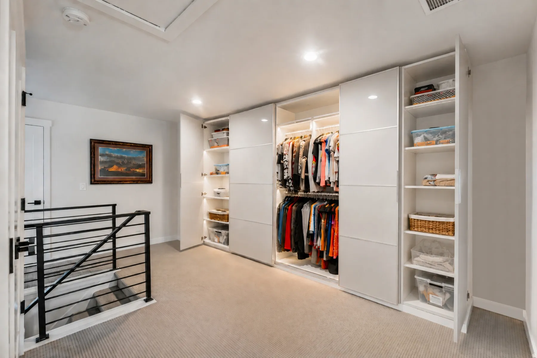 Integrated custom closet system featuring white panel doors, recessed lighting, varied shelving, and hanging storage