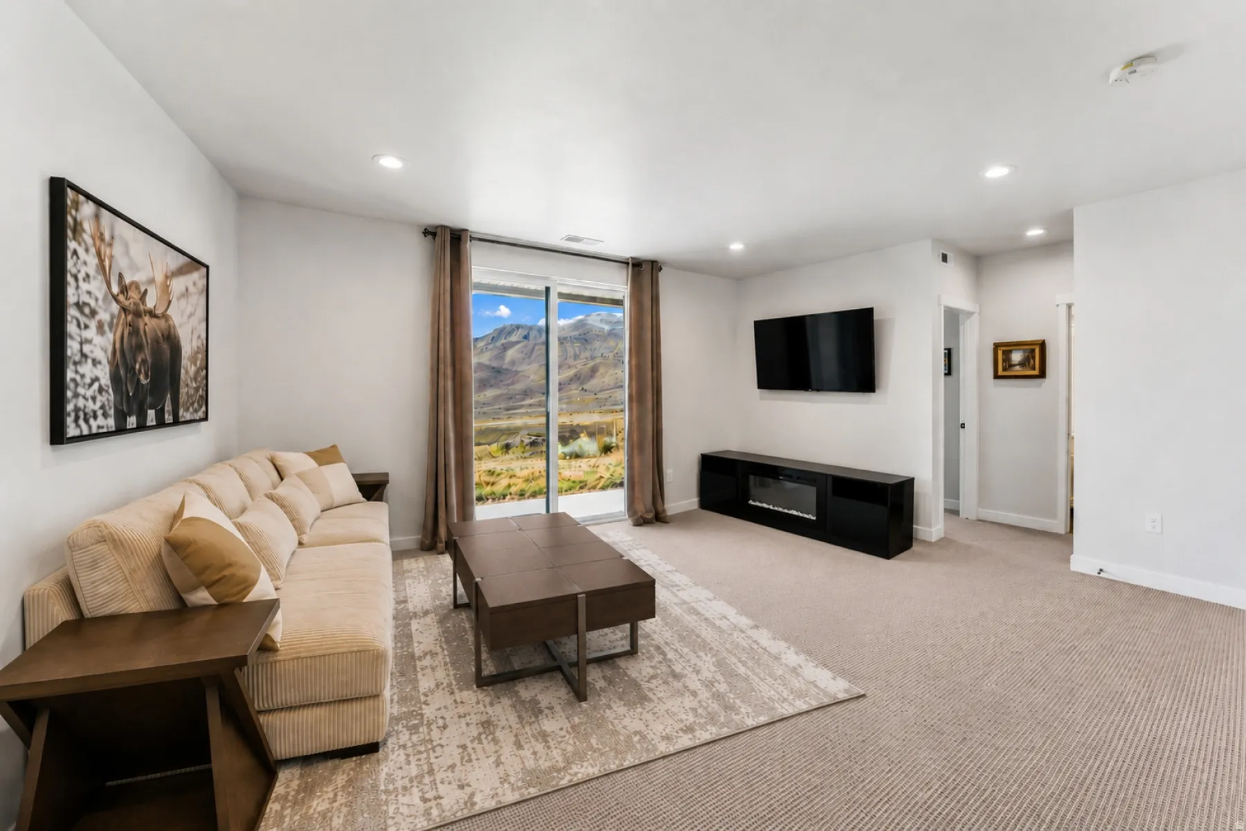 Living area featuring expansive glass sliding doors, recessed lighting, wall-mounted television, and a built-in media console with an electric fireplace
