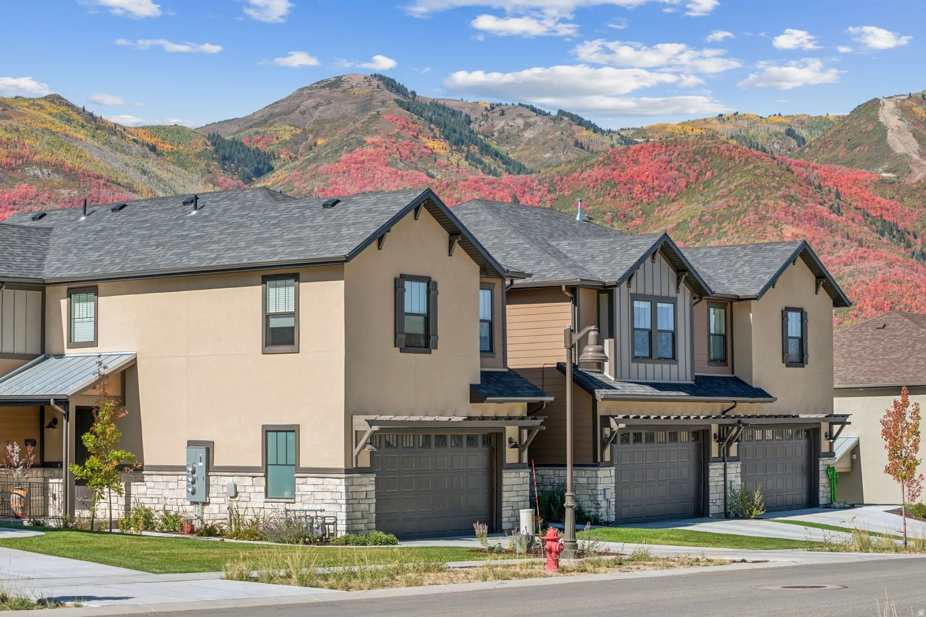 Contemporary townhome exteriors featuring stucco and stone accents, individual garages, and gabled roofs