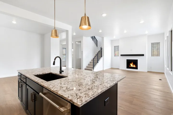 Kitchen island featuring a granite countertop, undermount sink, and black cabinetry