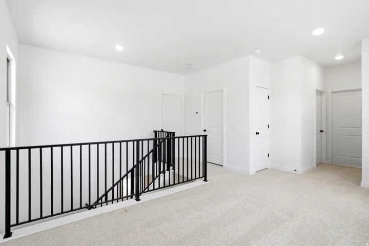 Spacious upper-level landing featuring light-colored carpeting, white walls, and recessed lighting