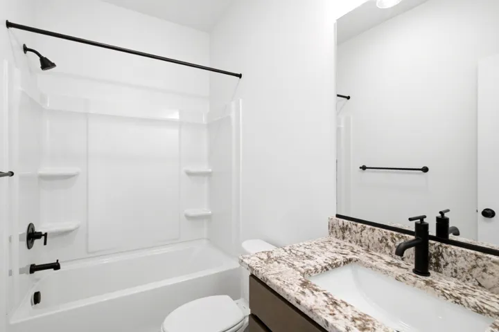 Bathroom featuring a white bathtub and shower combination with matte black fixtures