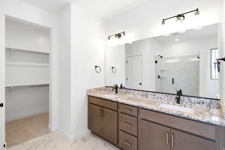 Bathroom featuring a double vanity with granite countertop, integrated sinks, and matte black fixtures
