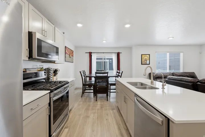 Kitchen showcasing light grey cabinetry with brushed nickel hardware, white countertops, and stainless steel appliances