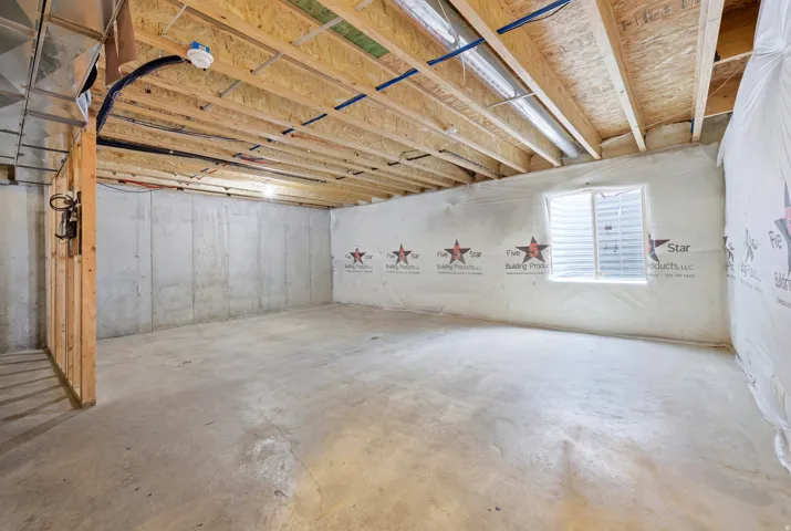 Unfinished basement featuring concrete flooring, exposed joist ceiling, and a single-pane window