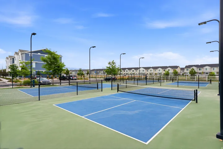Multiple pickleball courts featuring blue and green surfacing with perimeter fencing and nets