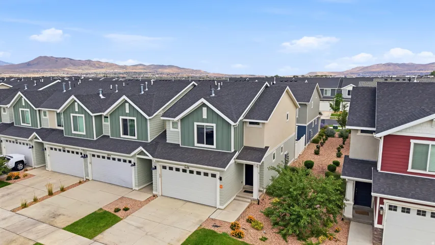 Rows of townhomes featuring varied siding colors, attached garages, and a uniform dark shingle roofline