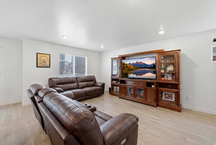 Bright living area featuring light wood-finish flooring, recessed lighting, and white walls