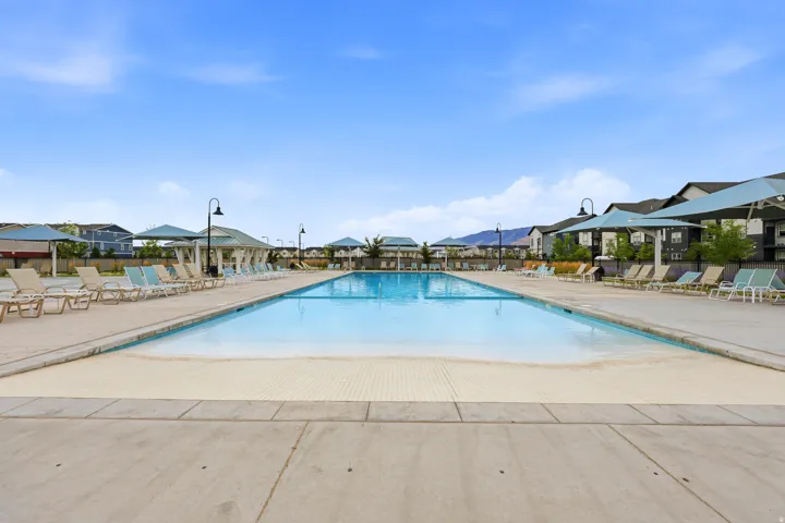 Expansive outdoor swimming pool with a shallow entry area, surrounded by concrete decking