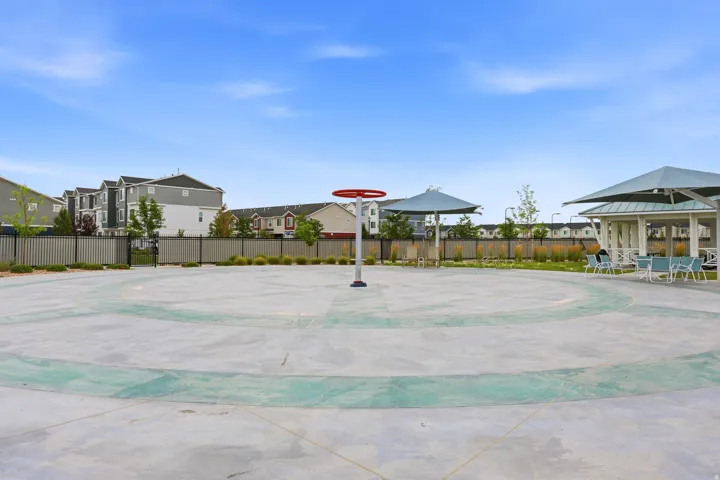 Community splash pad featuring a central water feature, surrounding seating areas, and a nearby covered pavilion