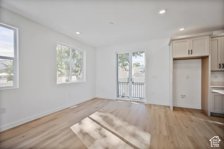 Light-filled interior featuring wood-finish flooring, recessed lighting, double-pane windows, sliding glass door, and shaker-style cabinetry