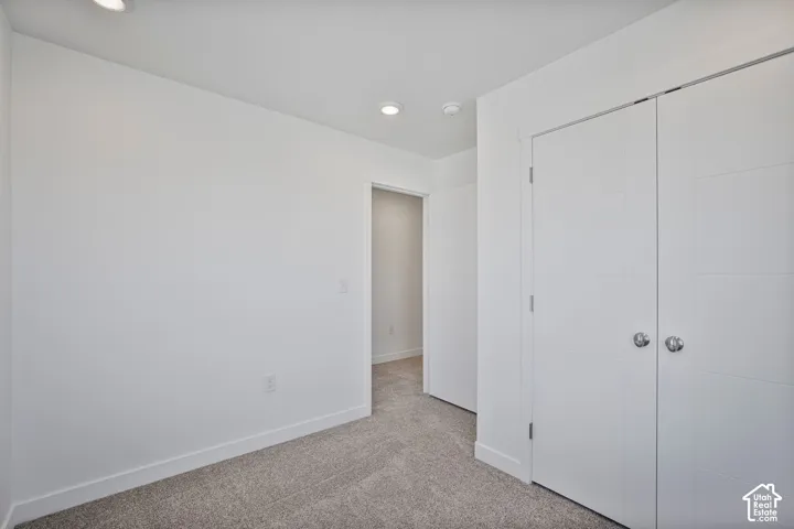 Neutral-toned wall-to-wall carpeting, recessed ceiling lighting, and double-door closet with horizontal panel detailing