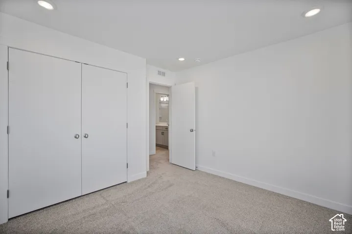 Neutral-toned carpeting, recessed ceiling lighting, and double-door closet with horizontal paneling