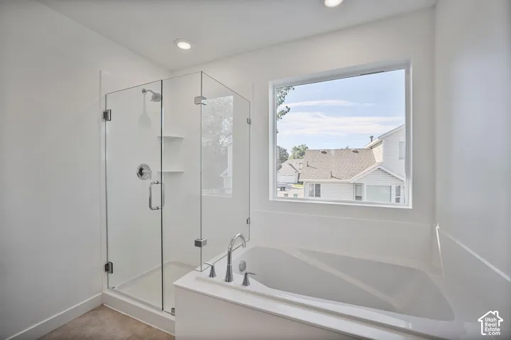 Bathroom featuring a soaking tub, separate glass-enclosed shower, built-in shelving, and recessed lighting