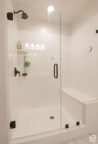 Frameless glass shower enclosure featuring matte black hardware, a built-in shower bench, and a corner shelf for storage