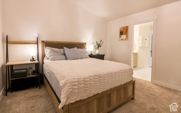 Carpeted bedroom with a wood-finish bed frame and white walls