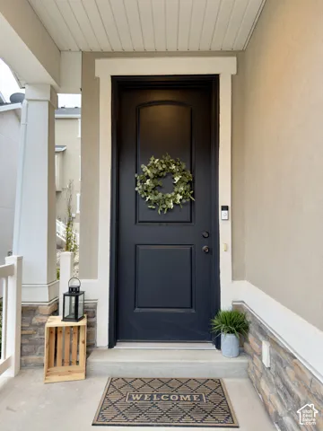 Front entry featuring a paneled door with an arched top detail, stucco siding, stone veneer accents, and a concrete porch