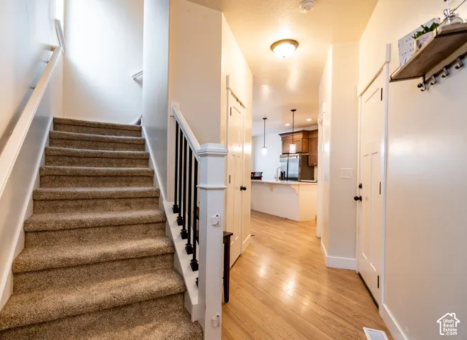 Carpeted staircase with white newel post and black spindles
