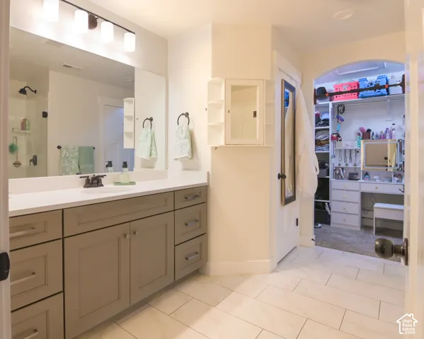 Bathroom featuring a single vanity with stone-finish countertop, undermount sink, and dark-finish faucet