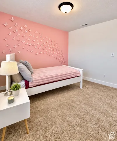 Bedroom featuring a distinctive accent wall with dimensional butterfly decor, plush carpet flooring, a white trim baseboard, and a flush-mount ceiling light fixture
