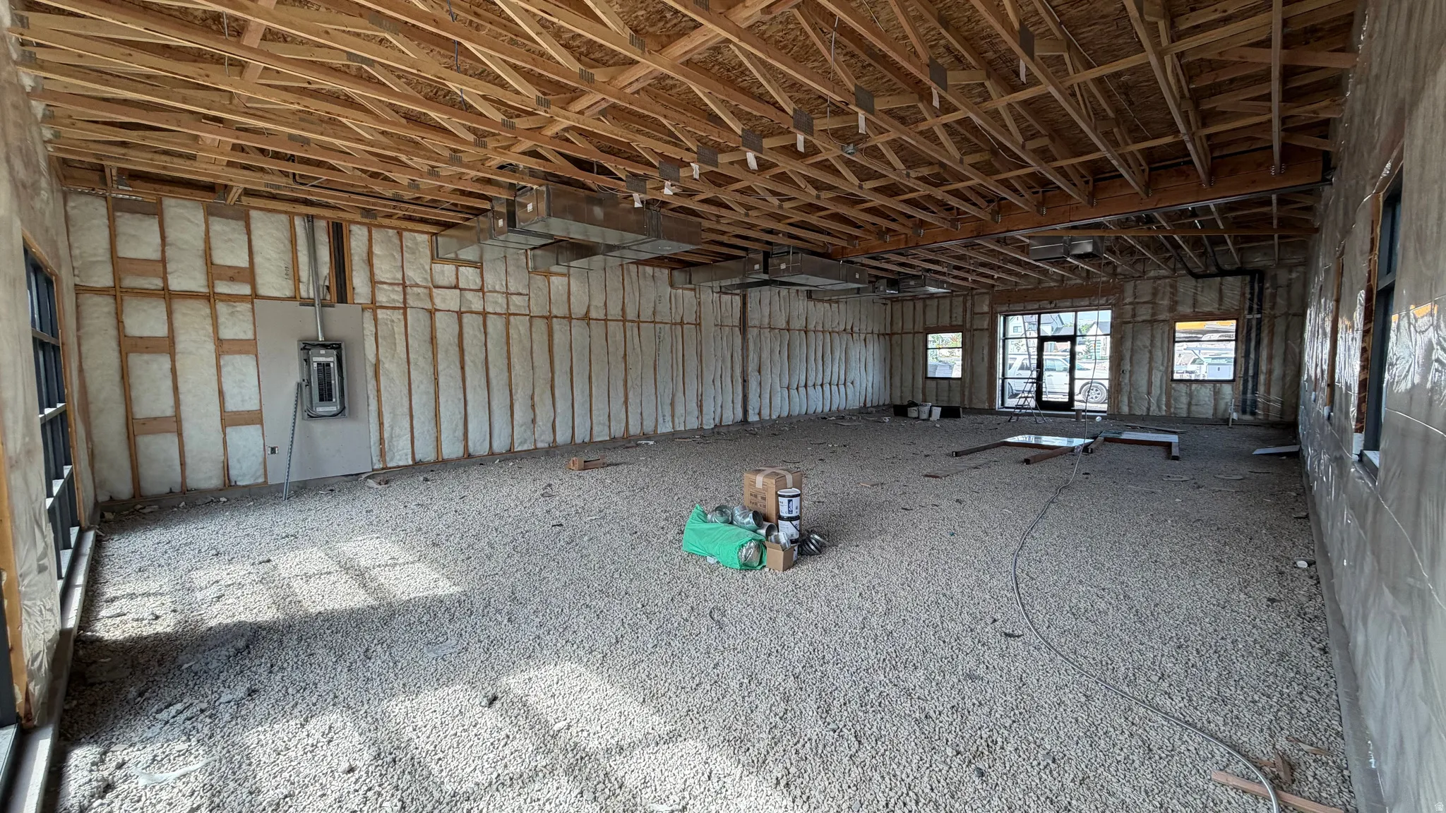 Exposed wood ceiling joists, open-concept floor plan, multiple window openings, and spray foam insulation