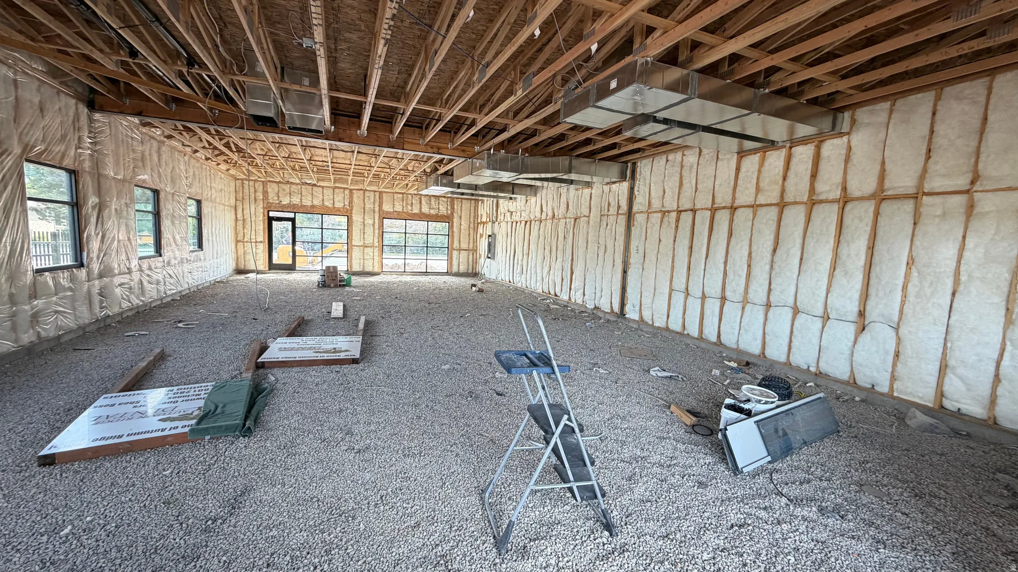 Exposed wood ceiling beams, multiple windows, two glass-paneled garage doors, and visible ductwork