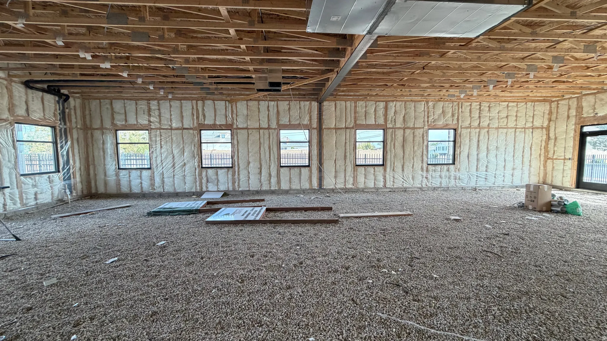 Exposed wood ceiling joists, multiple windows, spray foam insulation, and a sliding glass door