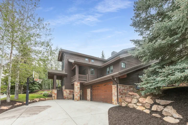 Multi-level exterior with dark wood siding, stone accents, and a two-car garage with wood-finish doors