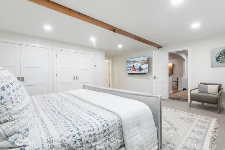 Recessed lighting illuminates a space featuring a wood beam accent
