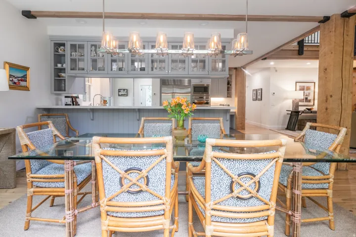 Dining area featuring a linear chandelier and exposed wood beams