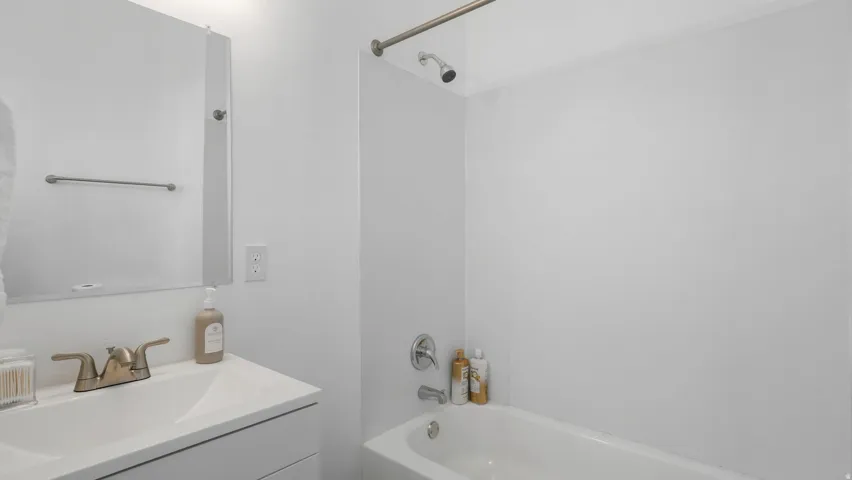 Bathroom featuring a white vanity with an integrated sink, brushed brass-finish faucet, and a wall-mounted mirrored medicine cabinet