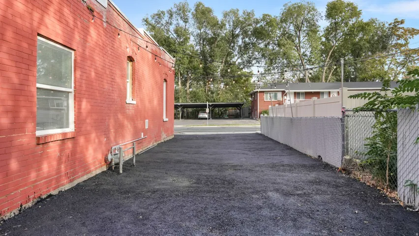 Paved lot with red brick exterior wall, white-framed windows, and string lighting