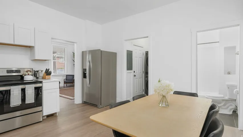 Kitchen and dining area featuring light wood-finish flooring, white cabinetry, stainless steel appliances, and a light-toned dining table